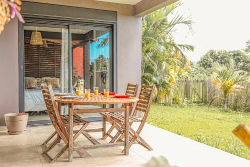a wooden table and chairs on a patio at Villa La Confiance - Vue mer-Jardin - By Sister Home in Saint-Benoît