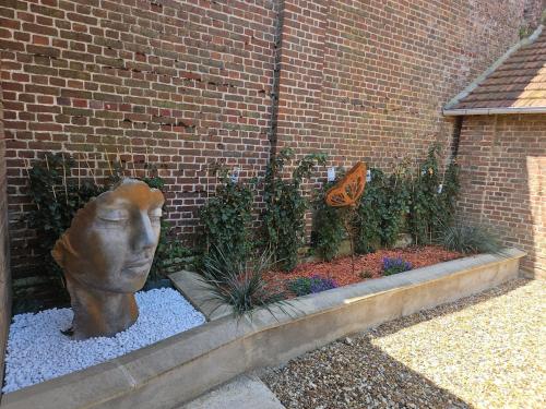 eine Statue eines Kopfes in einem Garten in der Unterkunft Maison dans corps de ferme Aéroport beauvais 14 minute 