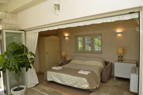 Un dormitorio con una cama y una planta. en Trulli Stella - Spectacular 3 bed Villa w/Private Pool, en Ceglie Messapica