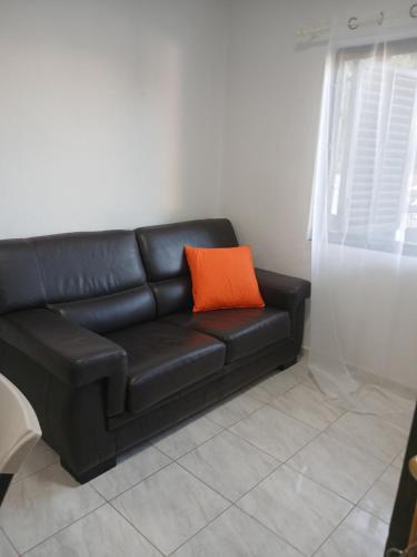 a black leather couch with an orange pillow on it at MonaLiza in Ulcinj