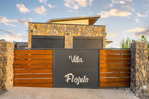 a villa with a wooden fence in front of a house at VILLA FLOJULO, sa piscine à débordement et sa vue à 180° sur l'océan in Le Portail