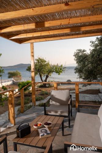 a patio with a table and a chair and the ocean at Avra Seafront Villa in Diliso
