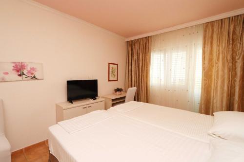 a bedroom with two white beds and a television at Hotel Pansion Villa Antonio in Orebić