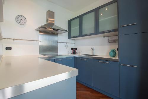 a kitchen with blue cabinets and white counter tops at Tavaredo House in Polpenazze del Garda