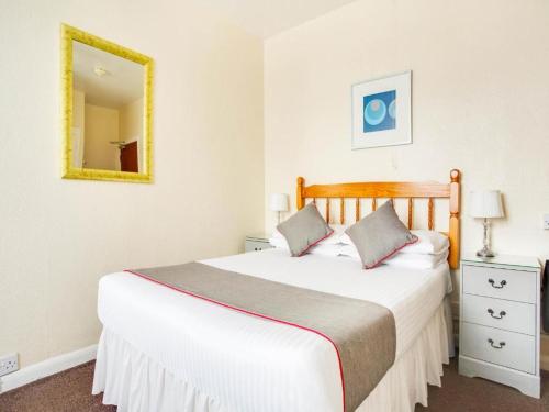 a bedroom with a large white bed with a mirror at GNDJ Hotel Skegness in Skegness