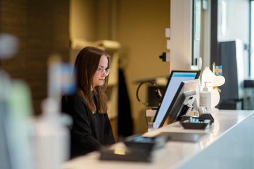 a woman sitting at a counter in front of a computer at Hotel Pommern in Mariehamn