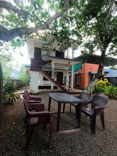 瓦尔卡拉Beach Combers Resort的房子前面的一张桌子和几把椅子