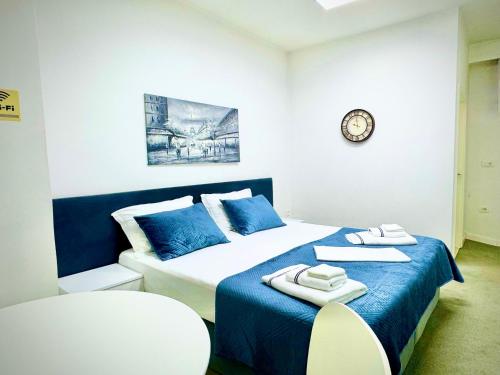 a bedroom with a blue and white bed and a clock at Tirana Center Apartments in Tirana