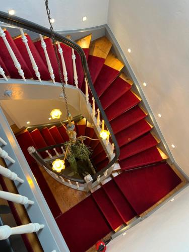 a staircase with red carpeted stairs with a chandelier at MY HOME Hotel Lamm Rottweil "Smart Home" in Rottweil
