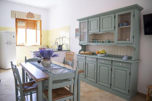 a kitchen with green cabinets and a table at filìa ϕιλία in Serranova
