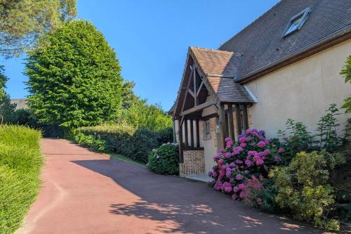 une maison avec des fleurs violettes à côté d'une allée dans l'établissement Villa Canet - Jacuzzi - Fireplace - Sauna EV 10P, à Gonneville-sur-Honfleur