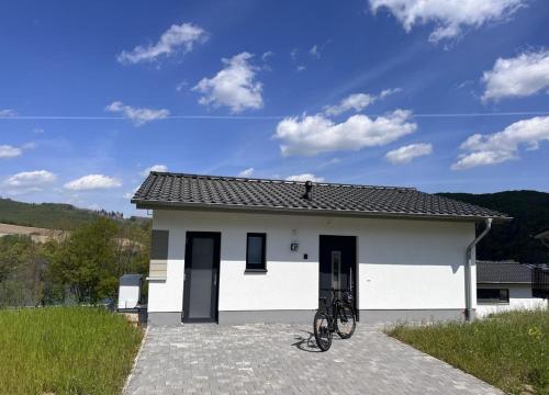 a bicycle parked in front of a white house at Ferienhaus Diemelblick 39 mit Hund - direkt am Diemelsee mit Sauna, Terrasse und Garten für bis zu 5 Personen in Diemelsee