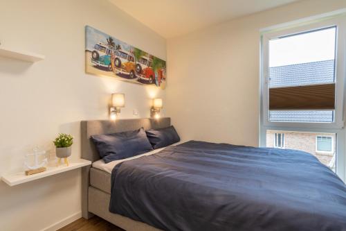 ein Schlafzimmer mit einem blauen Bett und einem Fenster in der Unterkunft Kellenhusen Tor 22 - strandnah mit Sauna und Balkon in Kellenhusen
