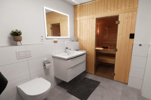 a white bathroom with a toilet and a sink at Lütte Koje - strandnah mit Sauna.Besonders familienfreundlich. in Butjadingen OT Tossens