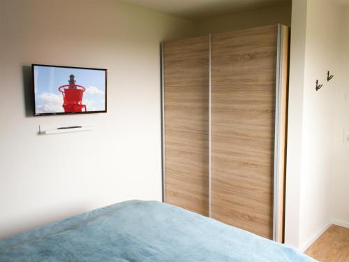 a bedroom with a bed and a wooden wardrobe at Auszeit im Sielhuus - Familienfreundliche Ferienwohnung mit Dachterrasse und Sauna in Fedderwardersiel