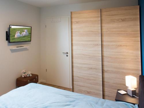 a bedroom with a large wooden closet with a tv on the wall at Auszeit im Sielhuus - Familienfreundliche Ferienwohnung mit Dachterrasse und Sauna in Fedderwardersiel