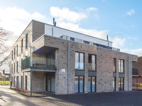 a brick building with a balcony on a street at Auszeit im Sielhuus - Familienfreundliche Ferienwohnung mit Dachterrasse und Sauna in Fedderwardersiel