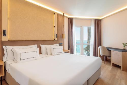 a bedroom with a large white bed and a desk at Melia Alicante in Alicante