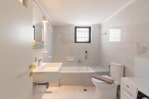 bagno bianco con vasca, lavandino e servizi igienici di Villa Svoronou Athens Riviera a Áyios Nikólaos