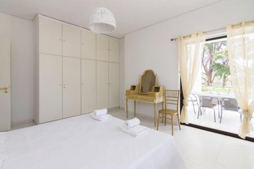 una camera da letto con due letti, una scrivania e una finestra di Villa Svoronou Athens Riviera a Áyios Nikólaos