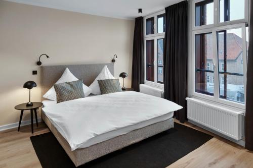 a bedroom with a large white bed and windows at Distillery Apartments in Lüneburg