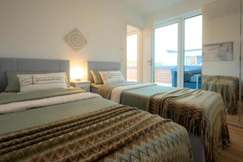 a bedroom with two beds and a window at Deichbude Tossens - Modernes Ferienhaus für 4 Personen in Butjadingen OT Tossens