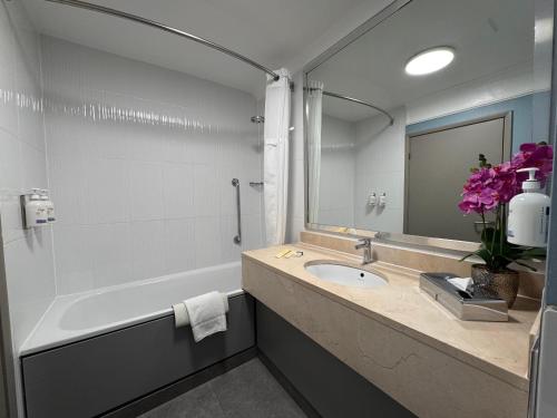 a bathroom with a tub and a sink and a mirror at Orida Hotels Newbury in Newbury