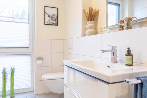 a white bathroom with a sink and a toilet at BeltBlick 19 – Exklusive Ferienwohnung mit Garten und Meerblick in Fehmarn