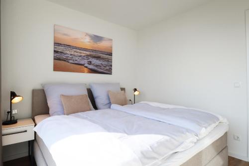 フェーマルンにあるBeltBlick 11 – Ferienwohnung mit unverbautem Meerblick & Dachterrasse!のベッドルーム1室(壁に絵画が描かれた白い大型ベッド1台付)