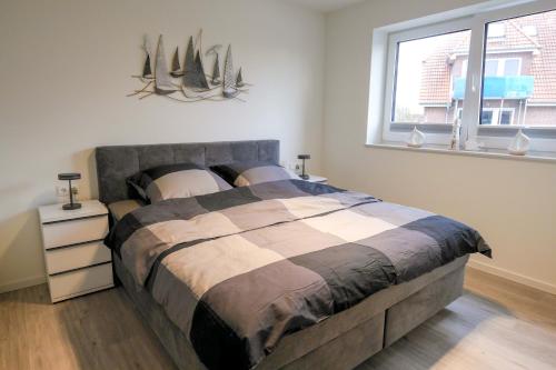 a bedroom with a large bed and a window at Küstenkind Dorum mit Sauna und Balkon - Hunde willkommen in Dorum