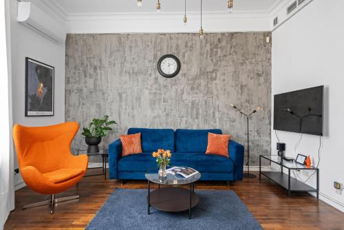 a living room with a blue couch and orange chairs at AS HOME Apartamenty - Grand Designer Loft 90m2 RYNEK 505 in Wrocław