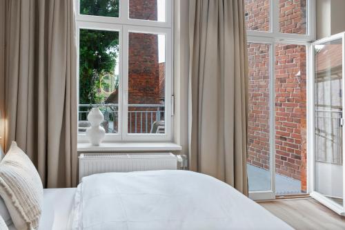 a bedroom with a bed and a large window at Distillery Apartments in Lüneburg