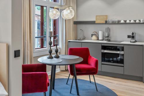 a kitchen with a table and two red chairs at Distillery Apartments in Lüneburg