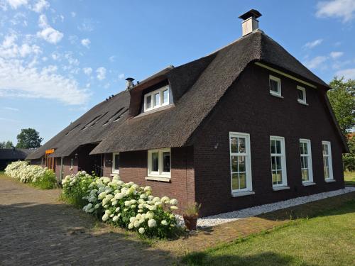 a black house with a thatched roof at De WiedenWeide in Wanneperveen