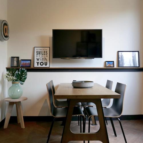 a dining room table with chairs and a tv on a wall at Getaway Studios Brussels Airport in Zaventem