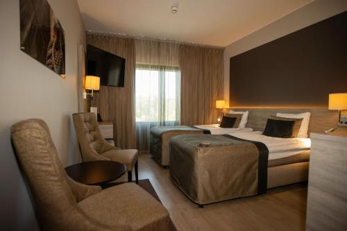 a hotel room with two beds and a chair at Hotel Pommern in Mariehamn