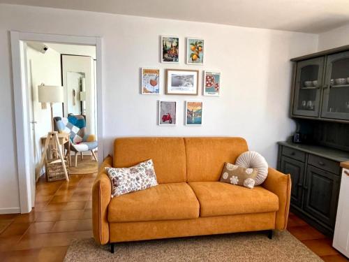 an orange couch in a living room with pictures on the wall at Vista Lago San Zeno in San Zeno di Montagna