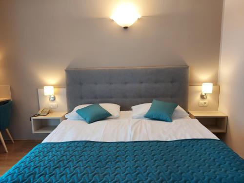 a bedroom with a large bed with two blue pillows at Belvedere Resort Hotels in Izola