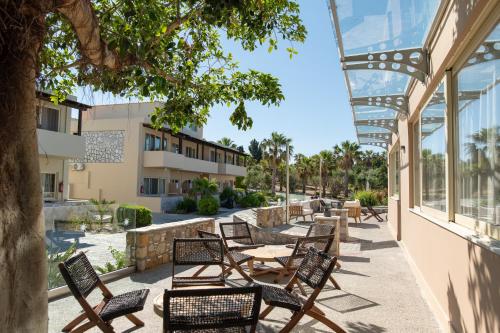 a patio with chairs and tables and a building at Achilleas Beach Hotel Adults Only in Mastichari