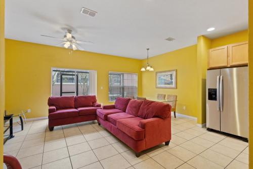 a living room with two red couches and yellow walls at SHVCK3 - Coral Cay Resort #3 - 4 Bed 3 Baths Townhome in Kissimmee