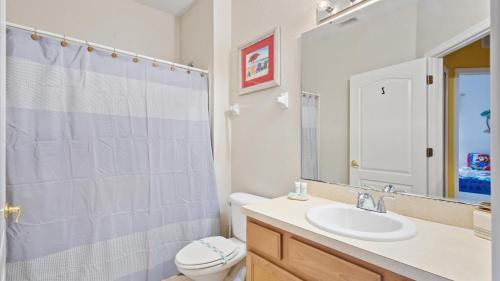 a bathroom with a sink and a toilet and a mirror at SHVCK3 - Coral Cay Resort #3 - 4 Bed 3 Baths Townhome in Kissimmee