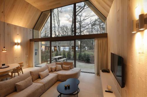 a living room with a couch and a large window at Lodge - 6 personen - Woodz Lodges in Heusden - Zolder