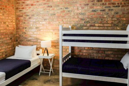 a bedroom with two bunk beds and a brick wall at Low Tide 8 Sleeper in Agulhas