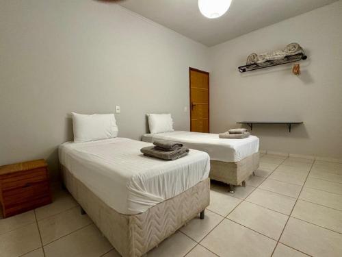 a bedroom with two beds and a table in it at Casa das Orquídeas Delfinopolis MG in Delfinópolis