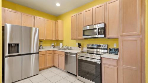 a kitchen with wooden cabinets and stainless steel appliances at SHVCK5 - Coral Cay Resort #5 - 4 Bed 3 Baths Townhome in Kissimmee