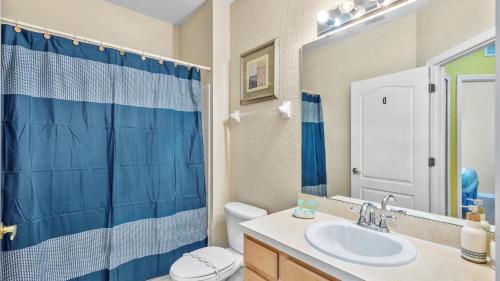 a bathroom with a blue shower curtain and a sink at SHVCK5 - Coral Cay Resort #5 - 4 Bed 3 Baths Townhome in Kissimmee