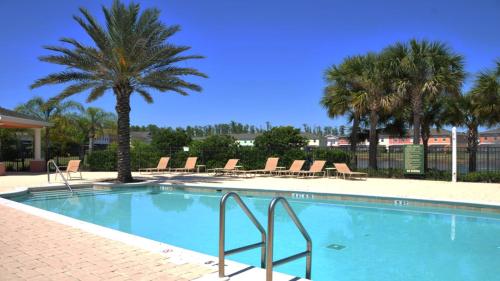 a swimming pool with chairs and palm trees at SHVCK5 - Coral Cay Resort #5 - 4 Bed 3 Baths Townhome in Kissimmee