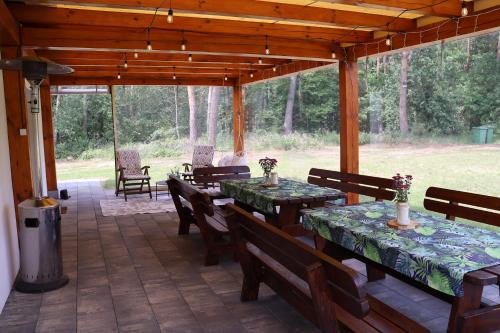 a covered patio with tables and chairs and a trash can at Dom w lesie przy stawach in Dylewo