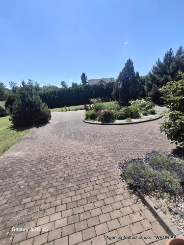 a brick walkway in a park with flowers and plants at Sunny Hill Apartment in Smętowo Chmieleńskie