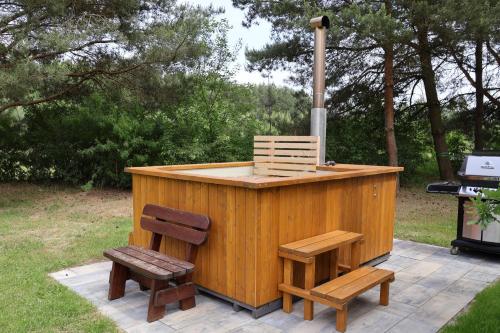a wooden outdoor bar with two chairs and a grill at Dom w lesie przy stawach in Dylewo
